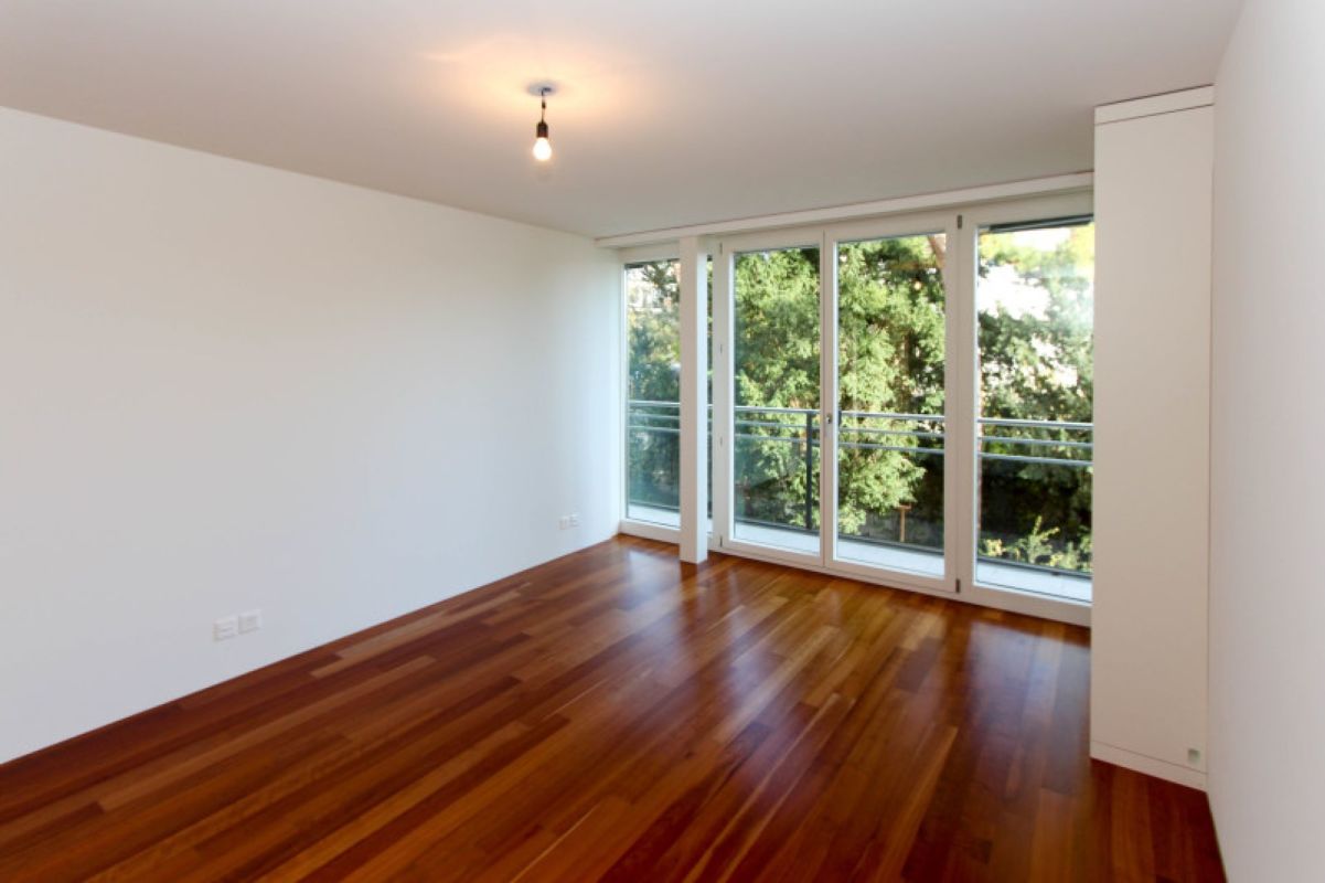 Heller leerer Wohnraum mit Balkon und Holzboden