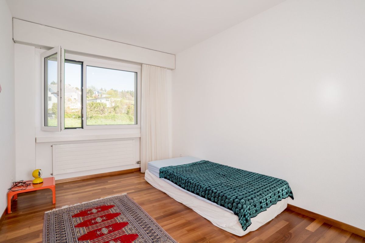 Helles Schlafzimmer mit Einzelbett und großem Fenster