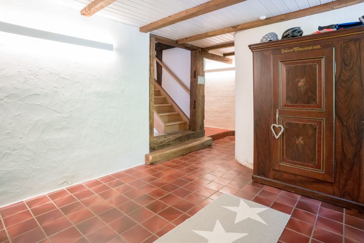 Rustikaler Flur mit Treppe und antikem Holzschrank