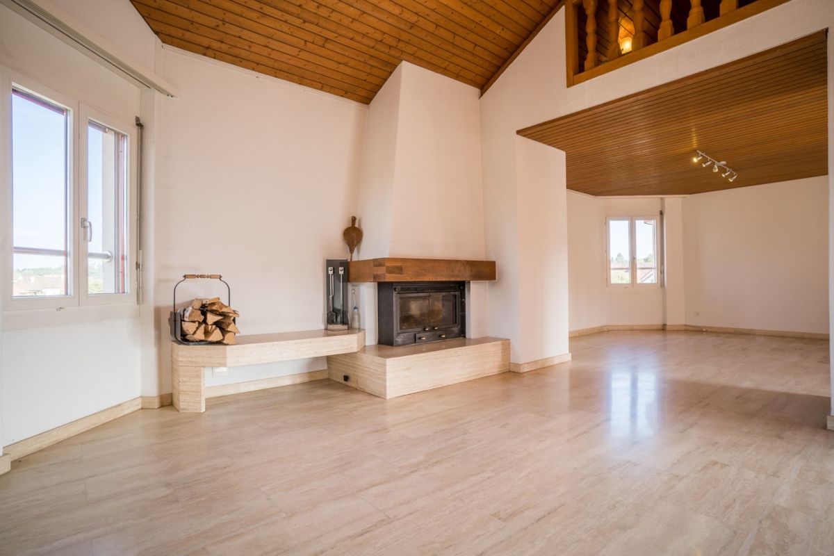 Großer Wohnraum mit Kamin und Holzdecke