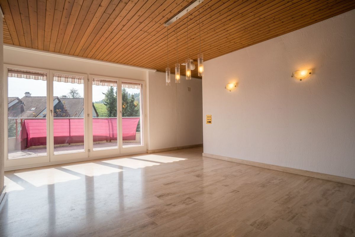 Heller leerer Wohnraum mit Balkon und Holzdecke