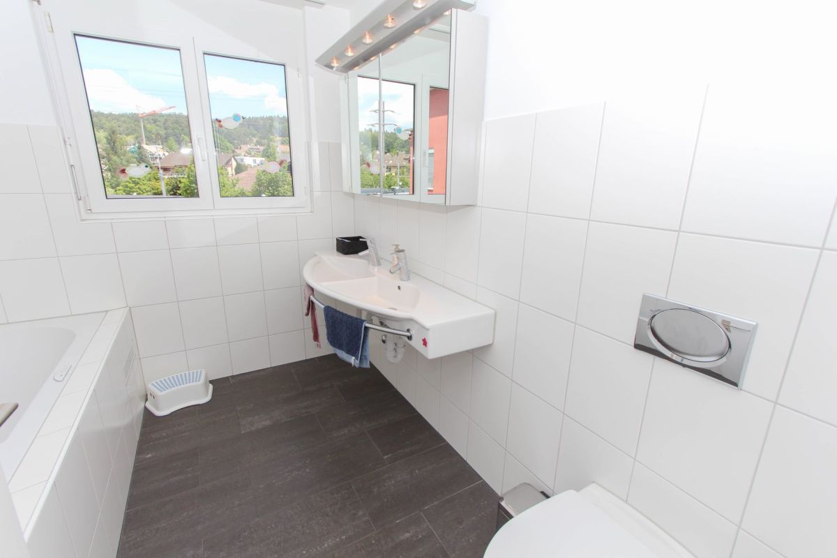 Helles Badezimmer mit Fenster und Badewanne