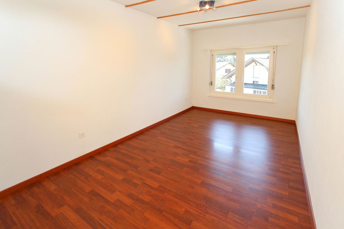 Leerer Wohnraum mit Parkettboden und Fenster
