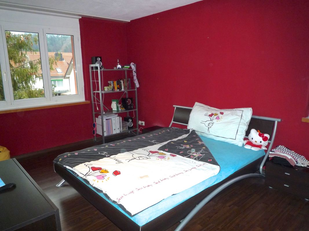 Jugendzimmer mit Bett und roter Wand