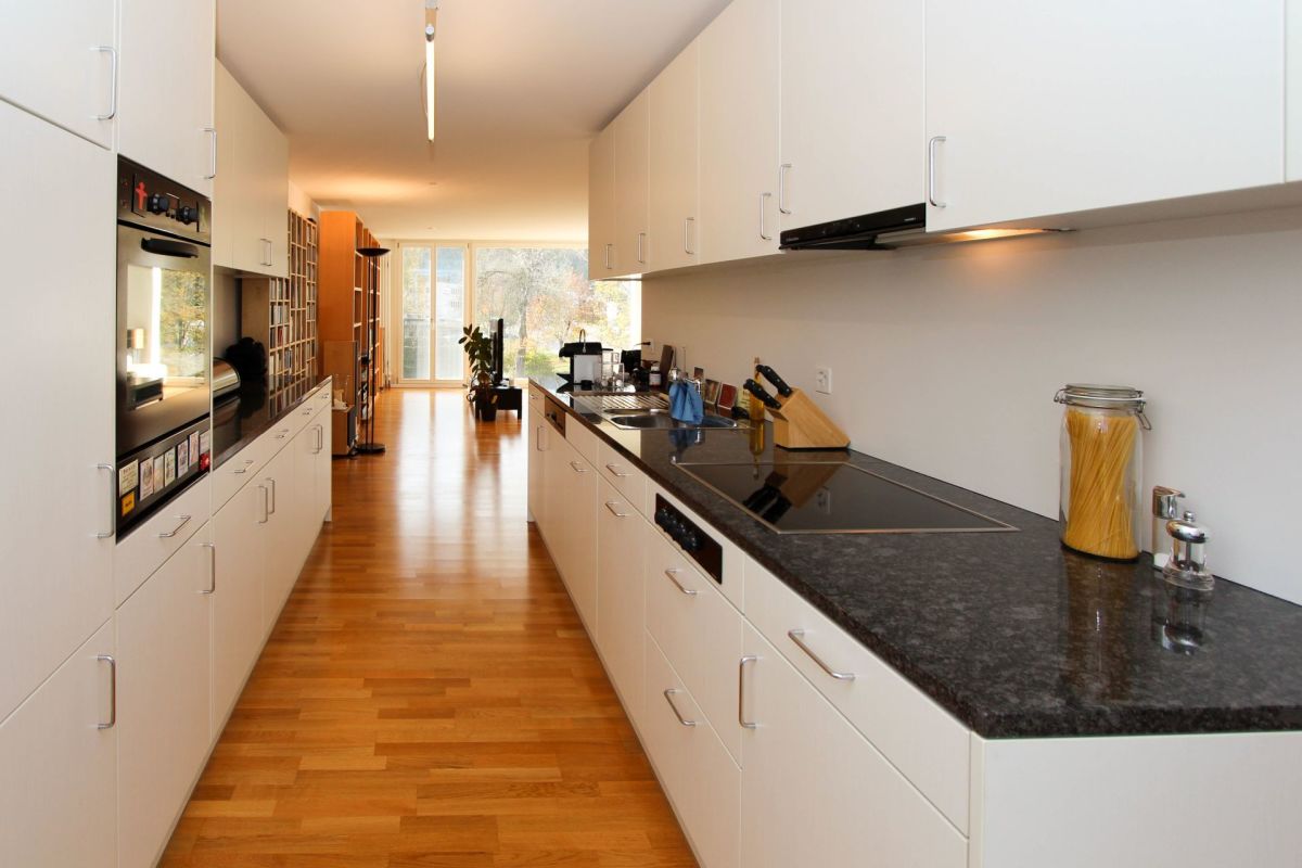 Moderne, helle Einbauküche mit Blick in den Wohnbereich