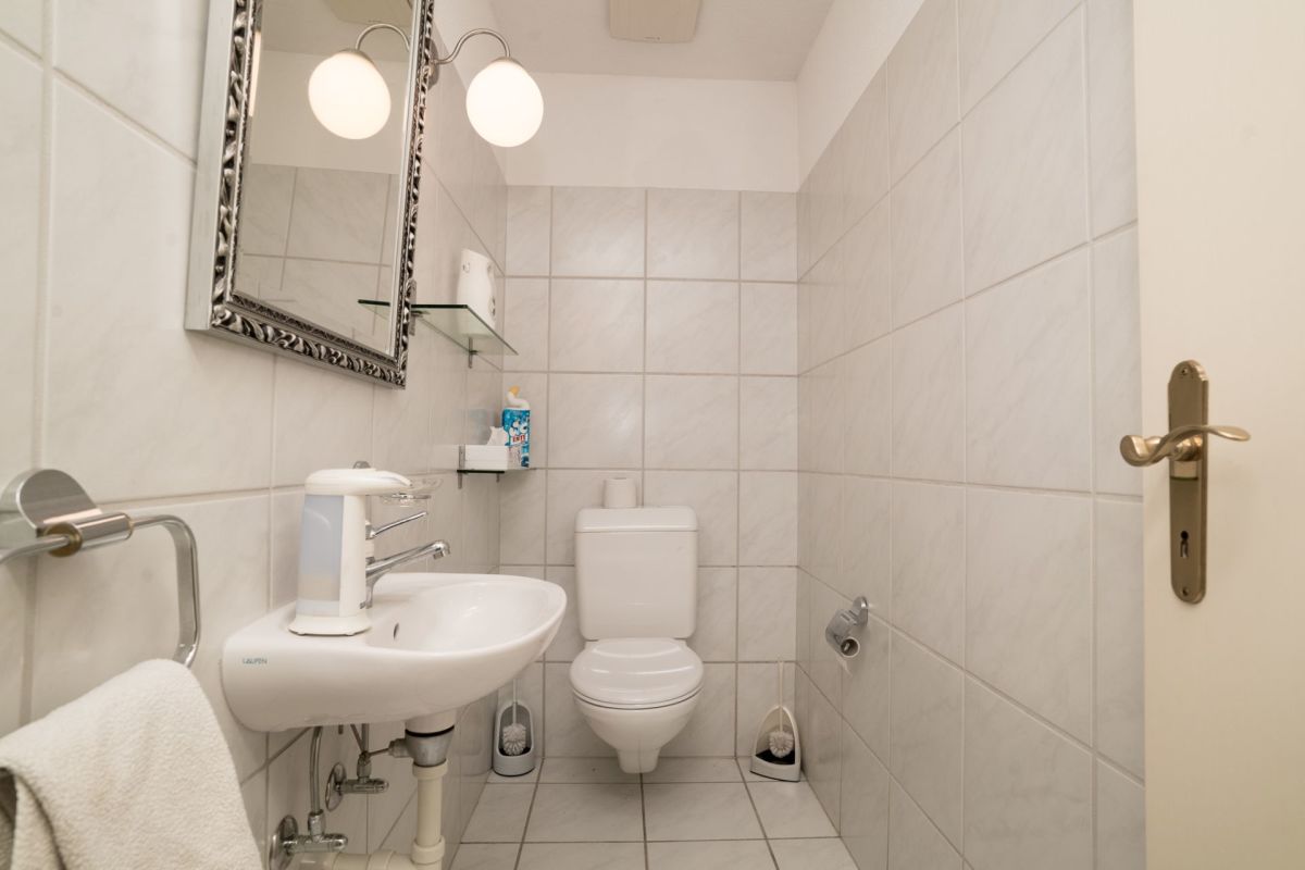 Kleines Gäste-WC mit weißer Fliesenverkleidung