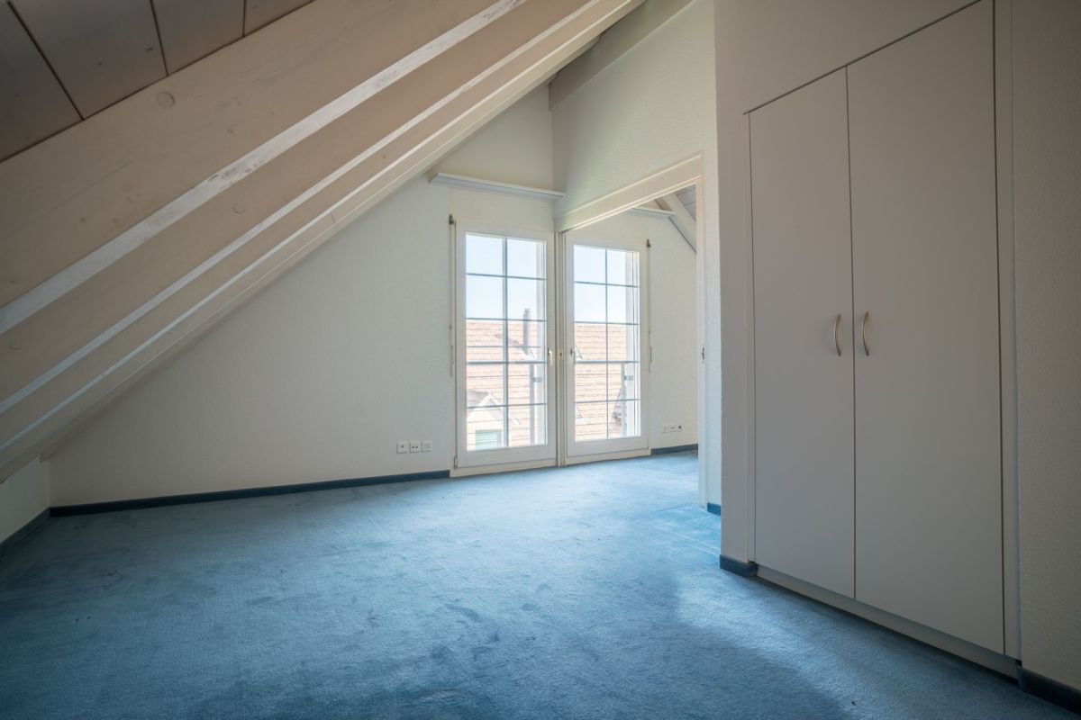 Dachgeschosszimmer mit Teppichboden und Einbauschrank