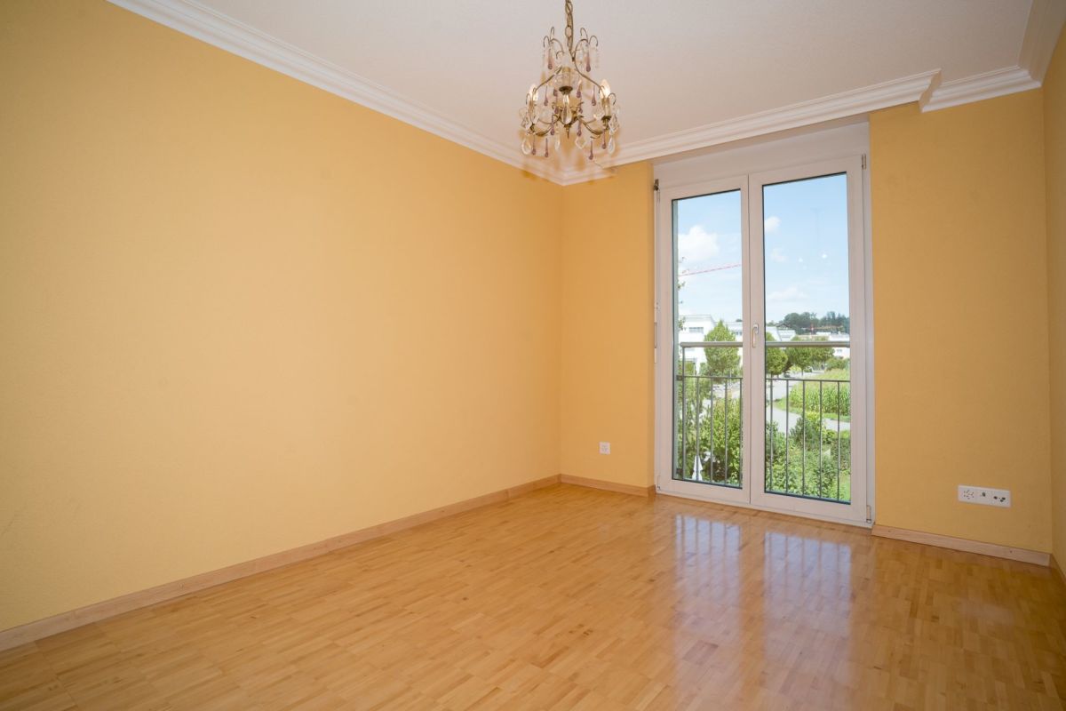 Heller leerer Raum mit Balkon- bzw. Fenstertür und Parkettboden