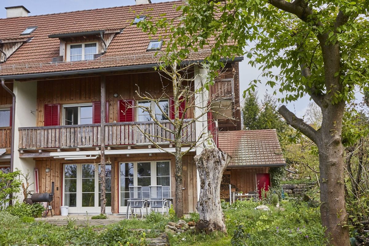 Gartenansicht eines Hauses mit Holzfassade und Balkon