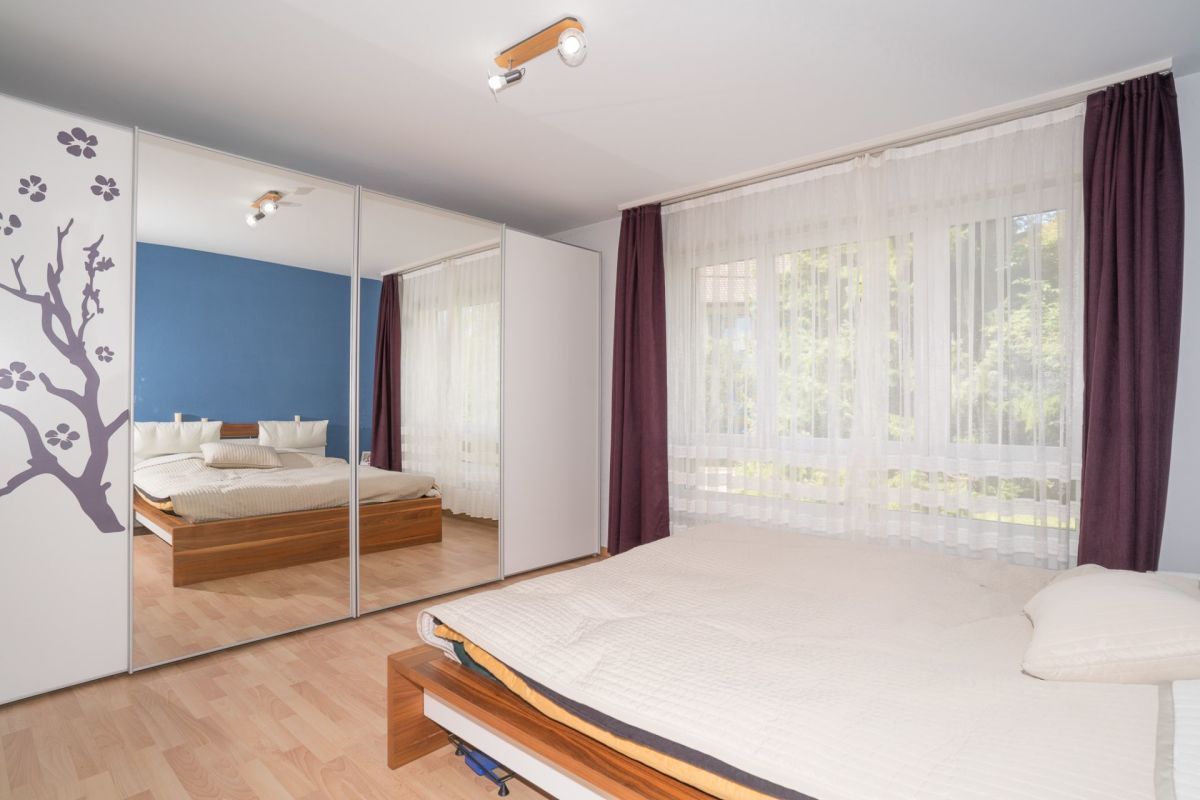 Schlafzimmer mit großem Fenster und Spiegelkleiderschrank