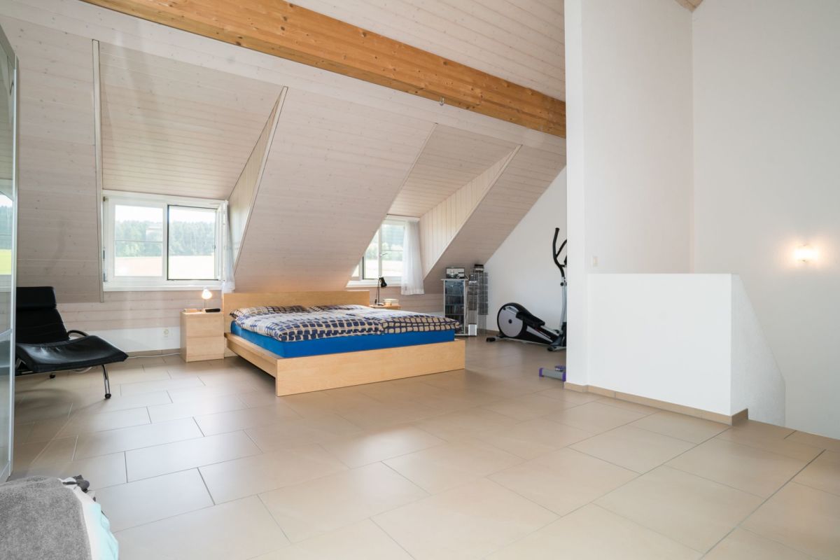 Dachgeschoss-Schlafzimmer mit sichtbaren Holzbalken