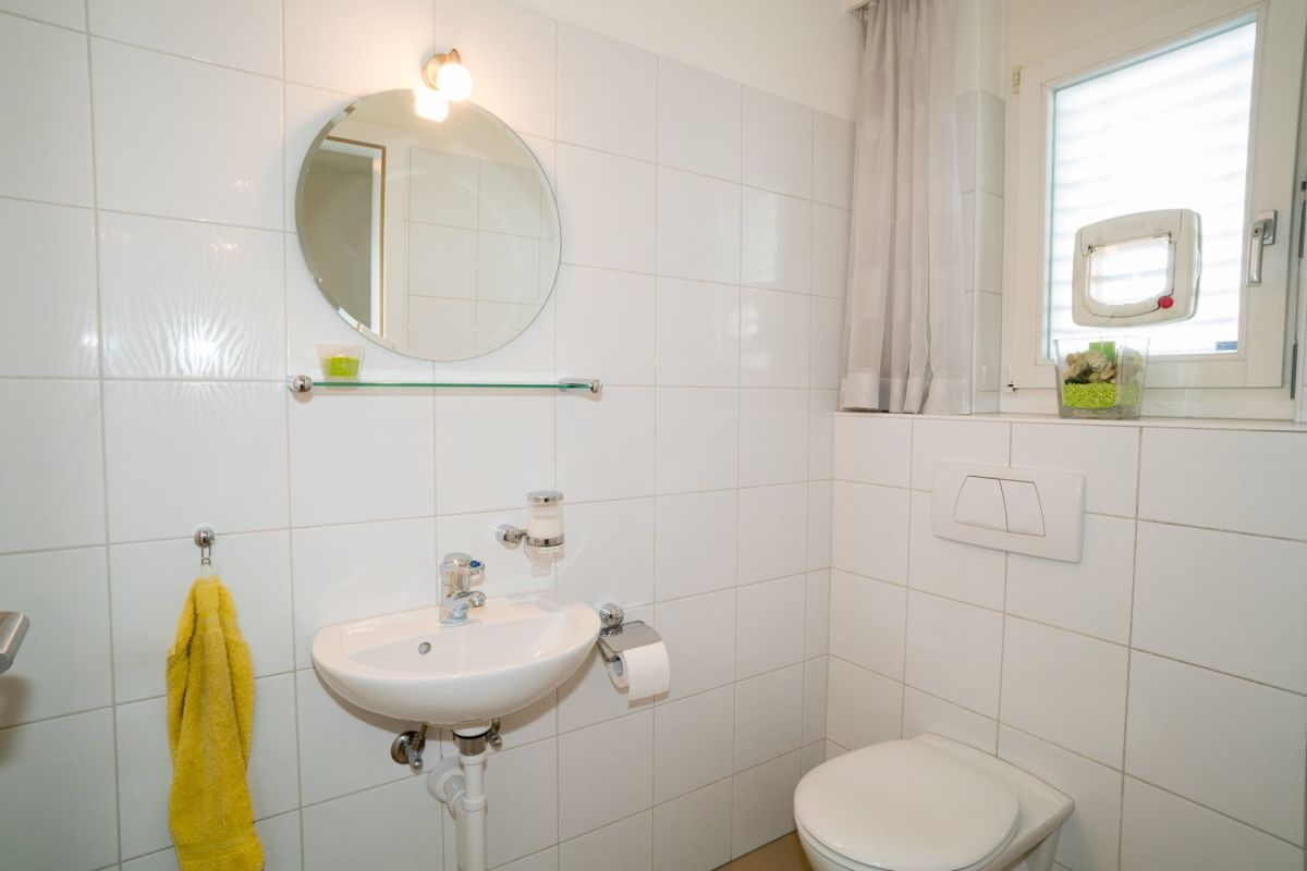 Gäste-WC mit rundem Spiegel und Fenster