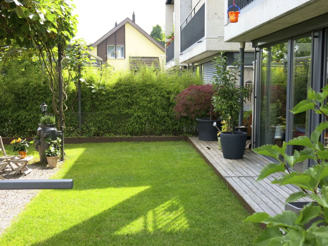 Garten mit Terrasse neben moderner Wohnanlage