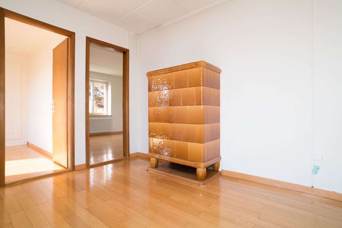 Heller leerer Raum mit Holzboden und Kachelofen