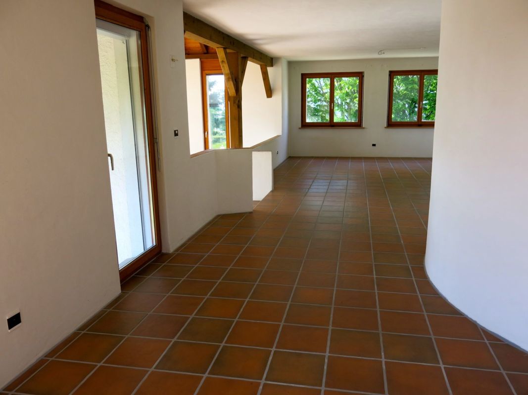 Leerer Wohnbereich mit Terrakottafliesen und Holzfenstern