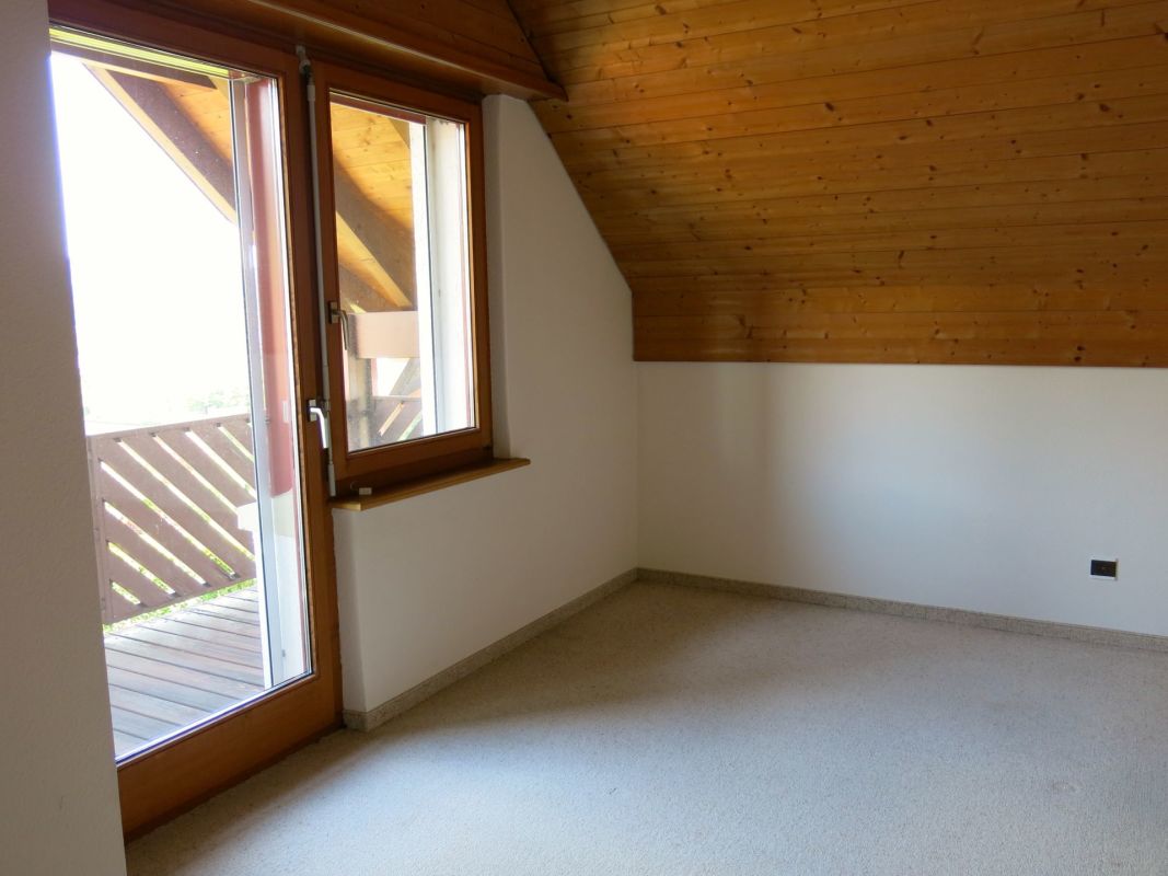 Leeres Dachzimmer mit Holzdecke und Balkonzugang