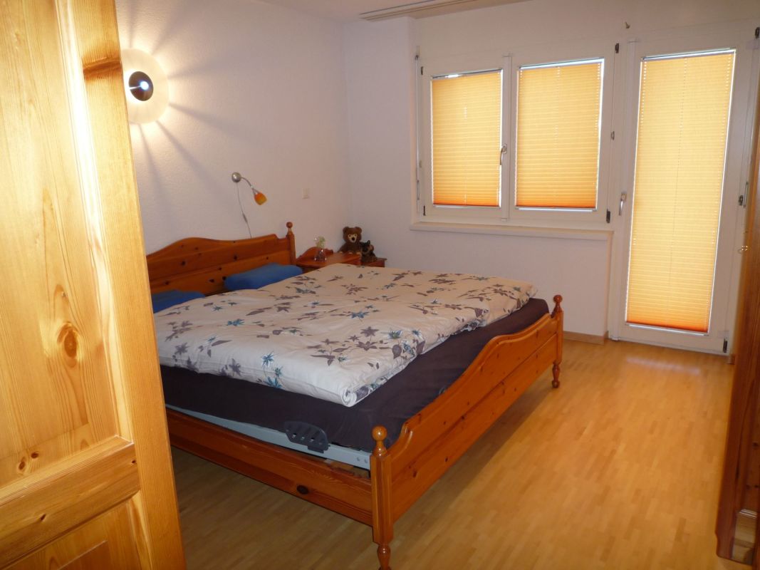 Helles Schlafzimmer mit Holzbetten und Jalousien