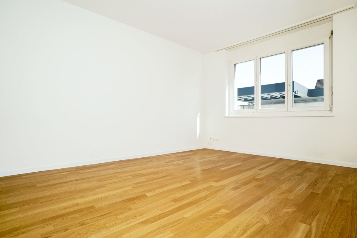 Leerer heller Raum mit Parkett und Fenster