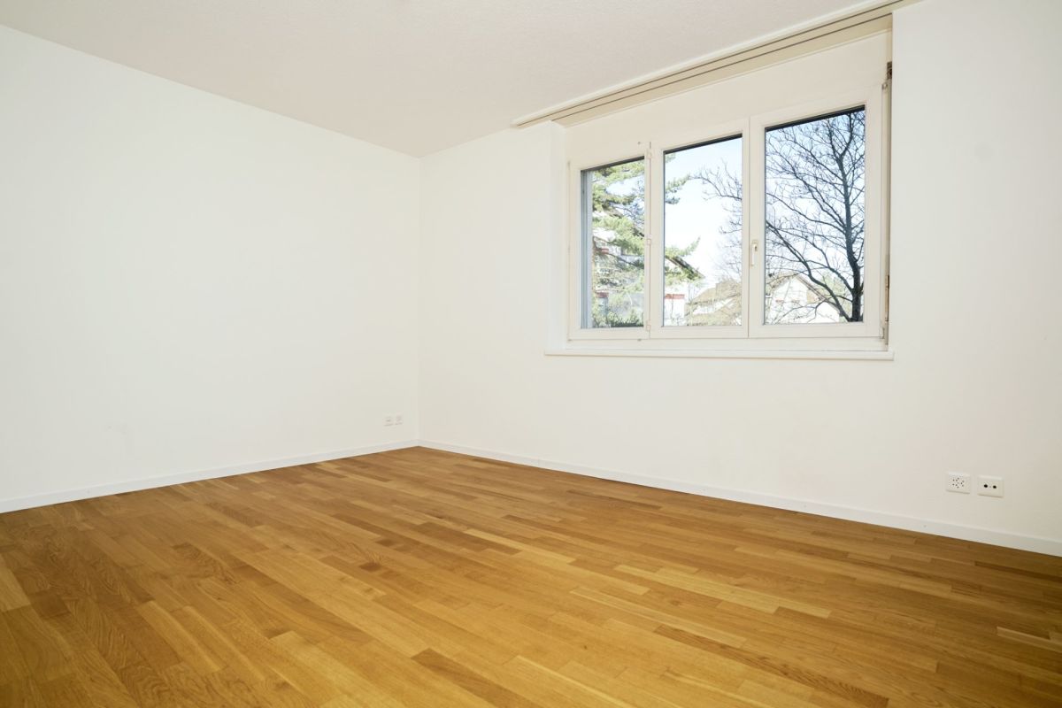 Leerer heller Raum mit Parkett und Fenster