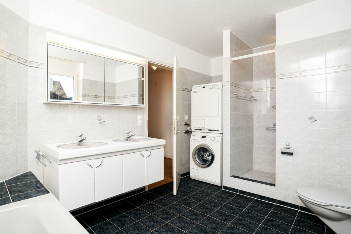 Helles Badezimmer mit Waschtisch, Dusche und Waschtrockner