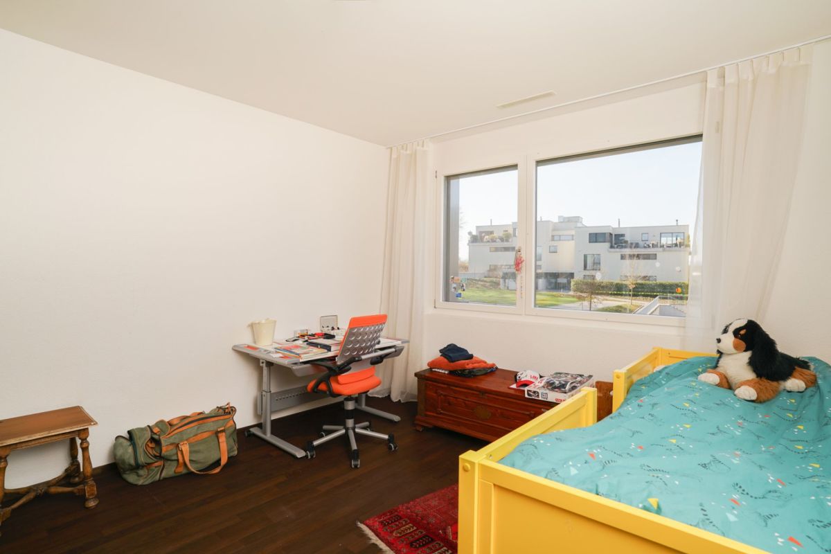 Helles Schlafzimmer mit großem Fenster und Kinderbett