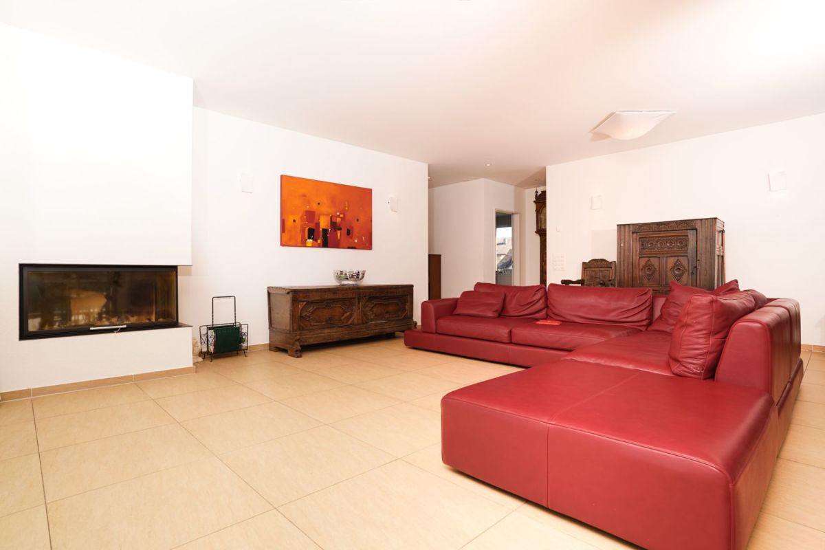 Wohnzimmer mit rotem Ledersofa und Kamin