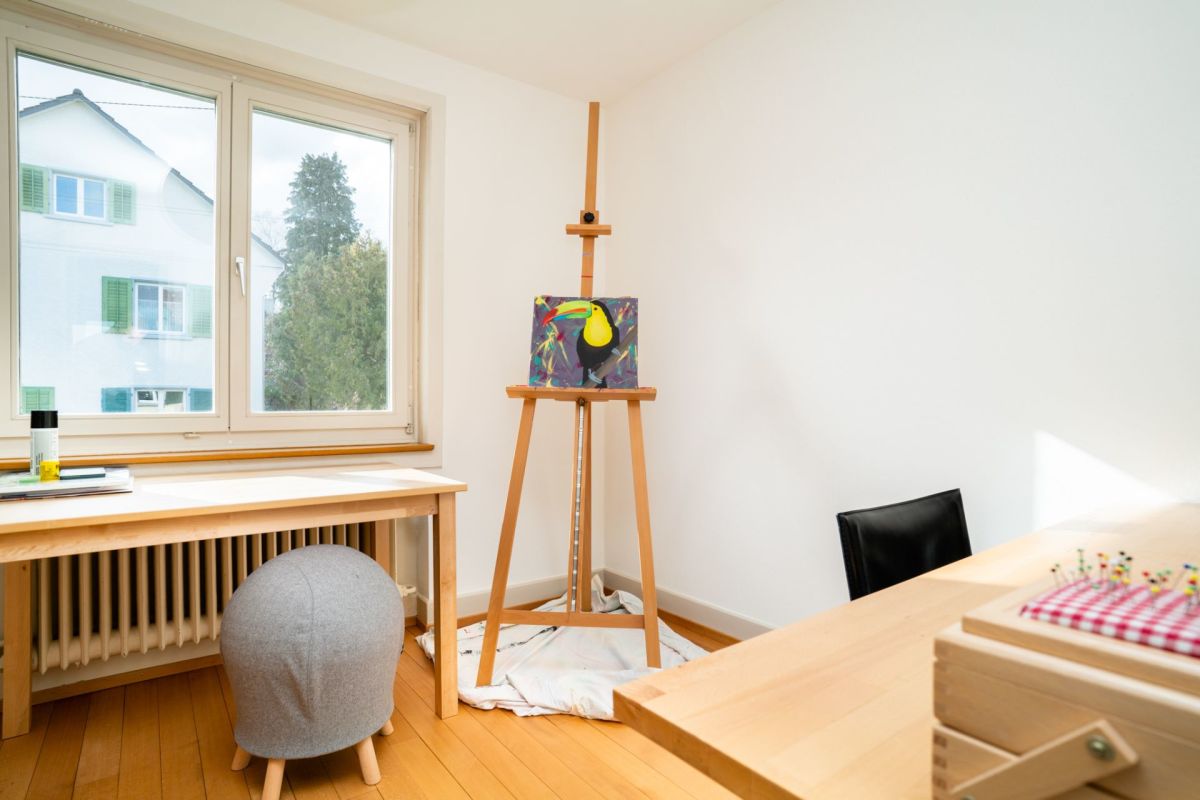 Heller Arbeits- und Kreativraum mit Fenster, Staffelei und Holzmöbeln