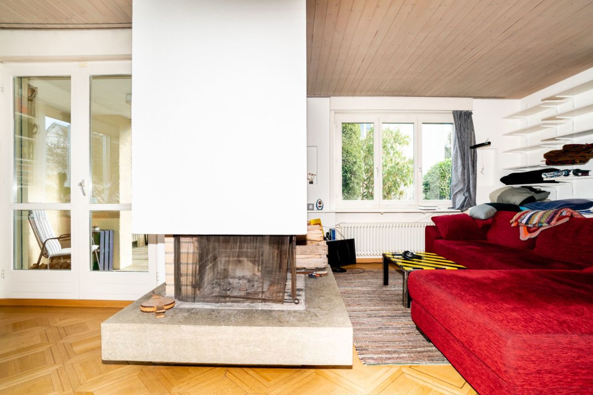 Wohnzimmer mit Kamin und roter Eckcouch