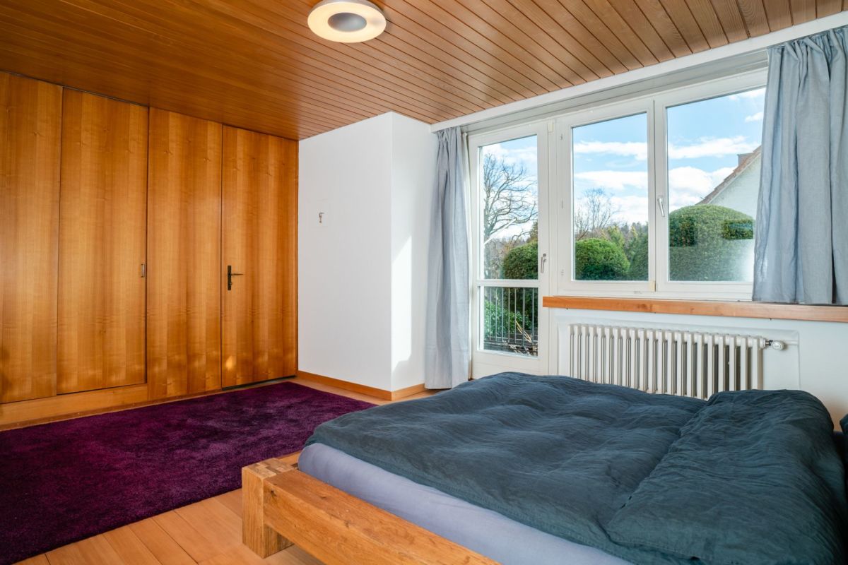 Schlafzimmer mit Holzverkleidung und großem Fenster