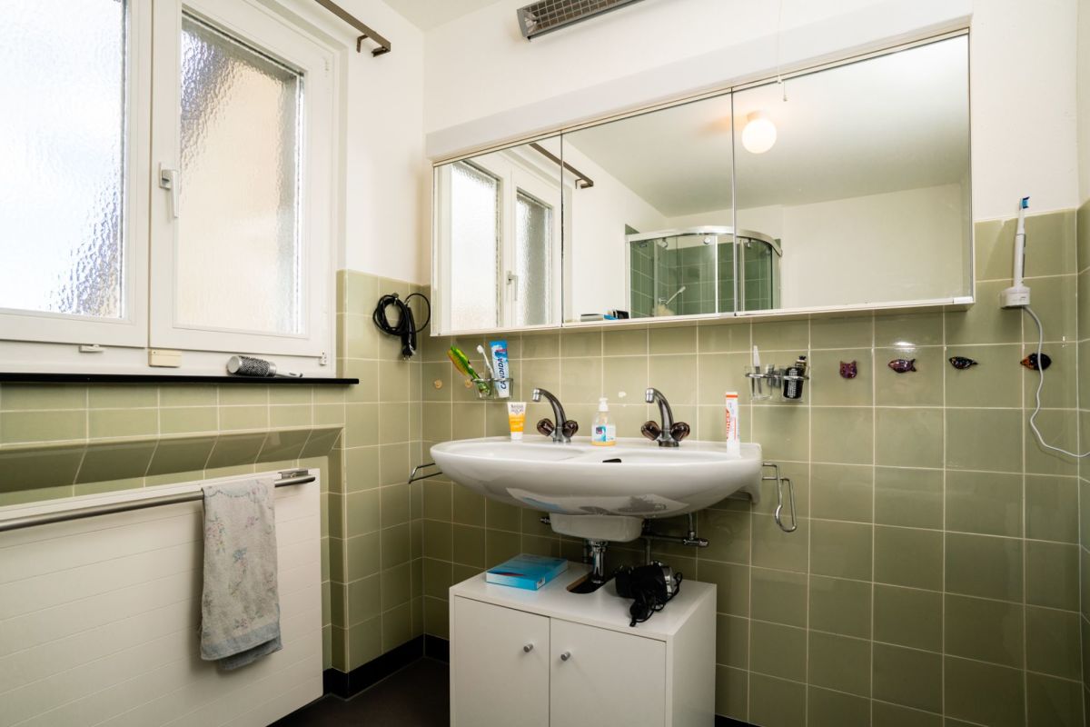 Badezimmer mit grünlichen Fliesen und Spiegelwaschtisch