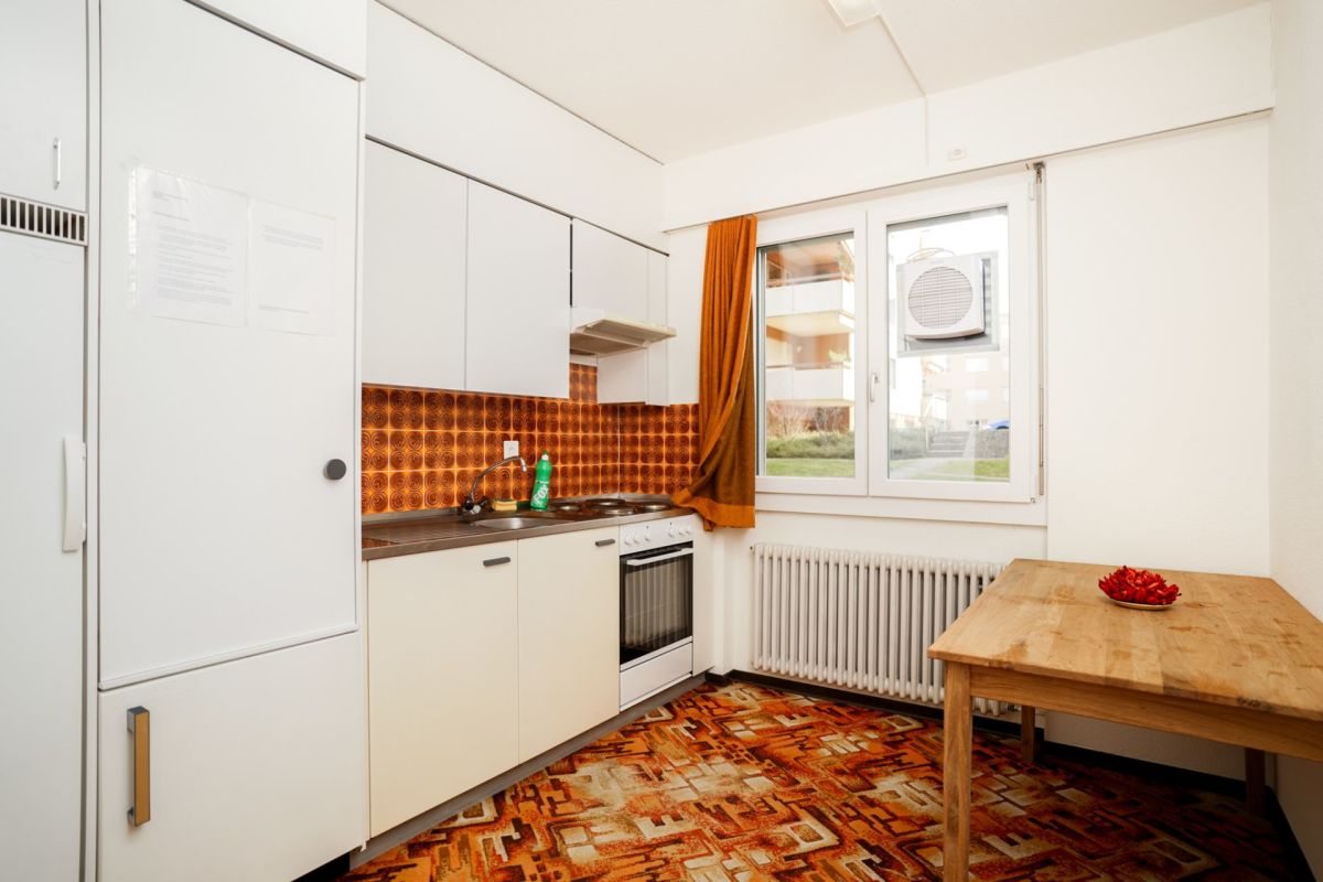 Kleine Küche mit farbigem Retro-Boden und Blick zum Fenster