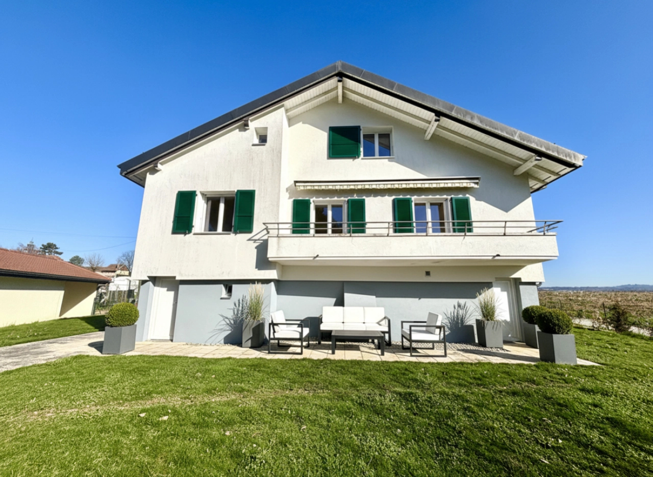 Außenansicht eines Einfamilienhauses mit Balkon und Garten