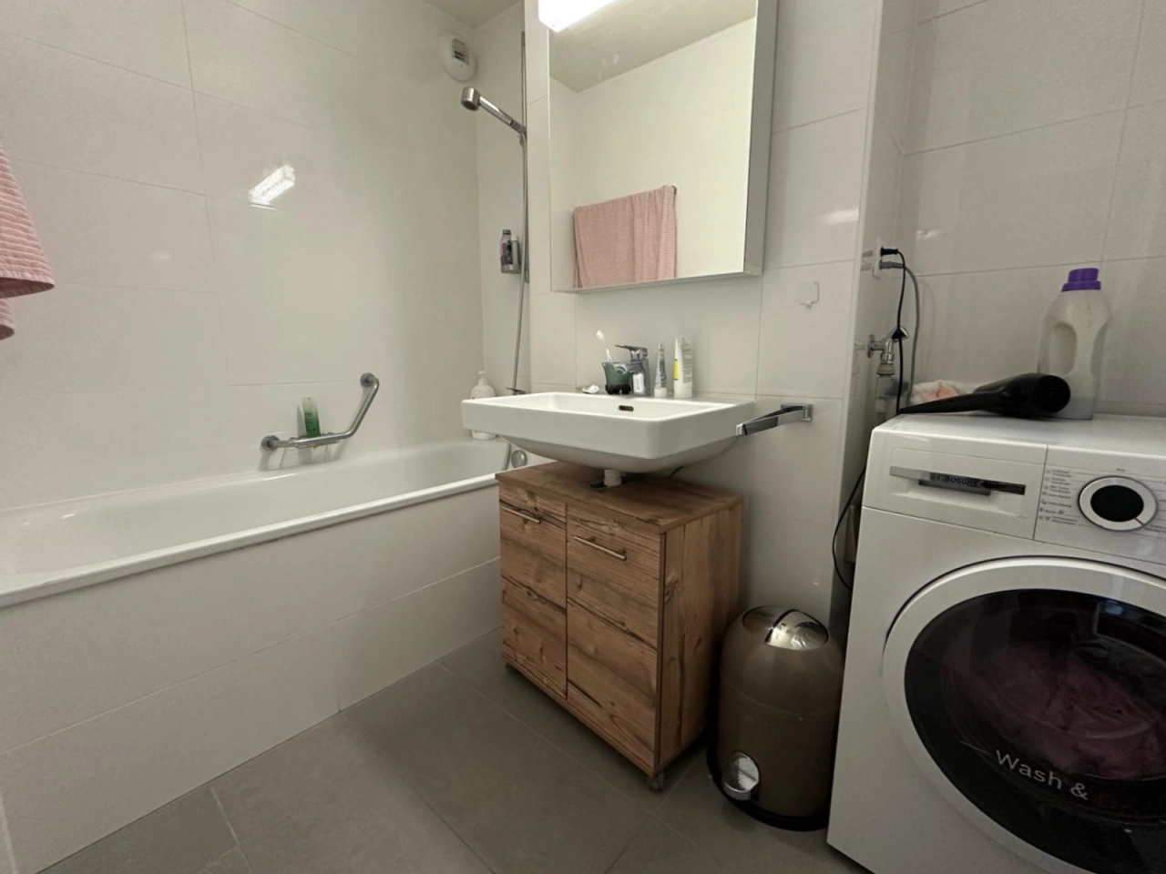 Badezimmer mit Badewanne, Waschtisch und Waschmaschine
