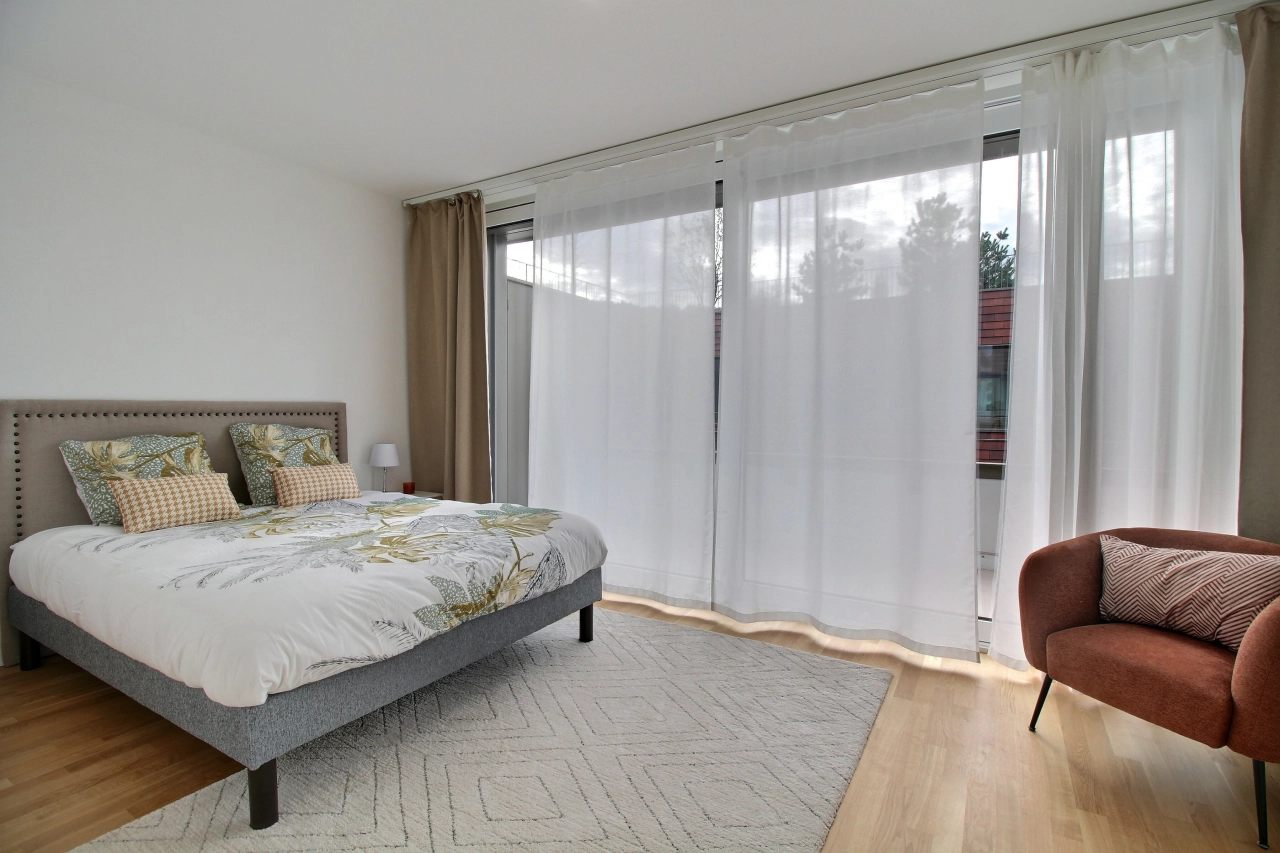 Helles Schlafzimmer mit großem Fenster und gemütlicher Einrichtung