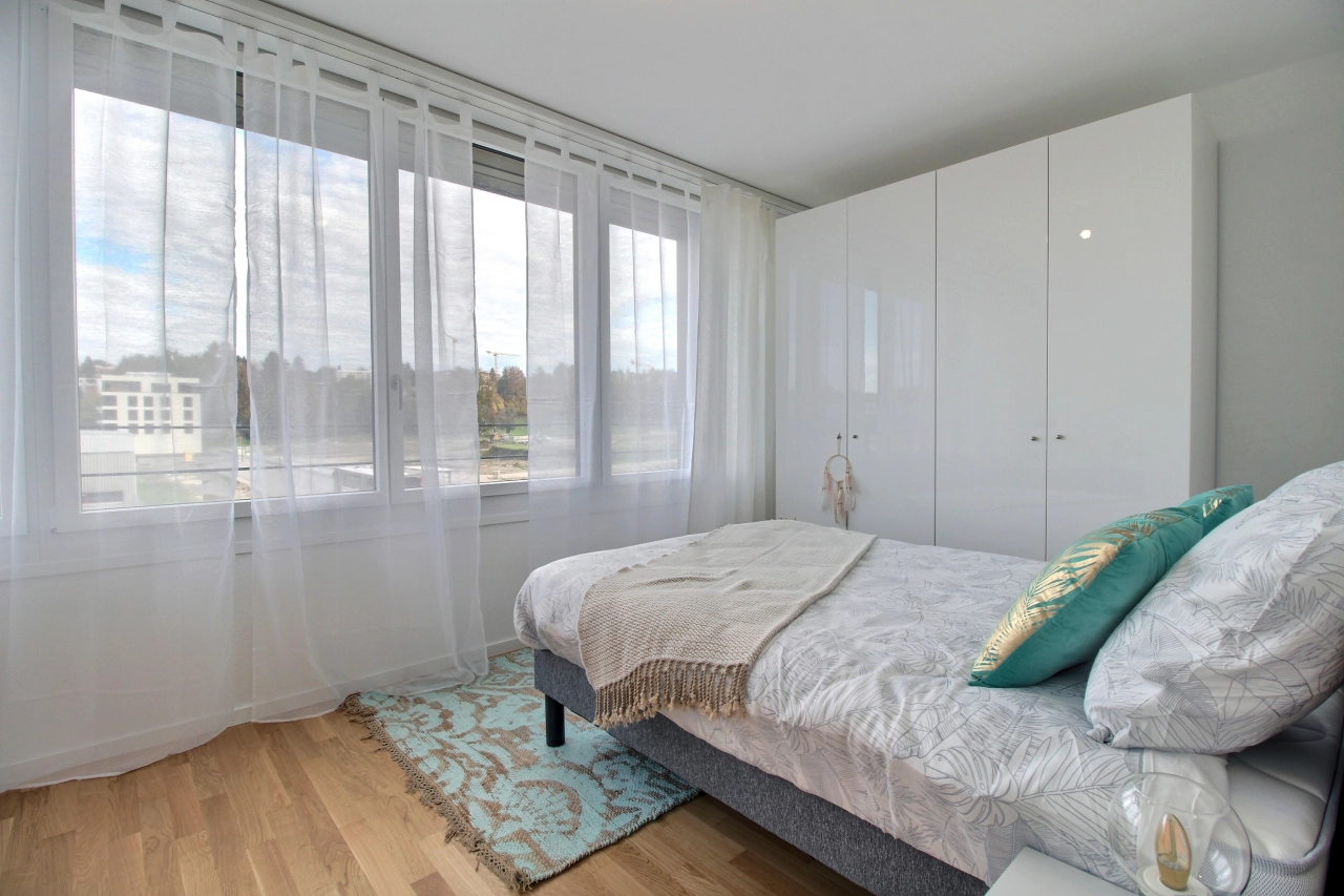 Helles Schlafzimmer mit großem Fenster und weißem Kleiderschrank