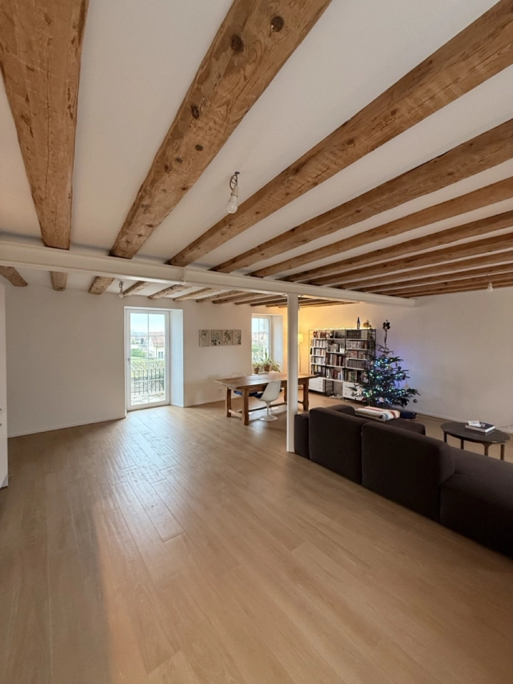 Offener Wohnraum mit sichtbaren Holzbalken