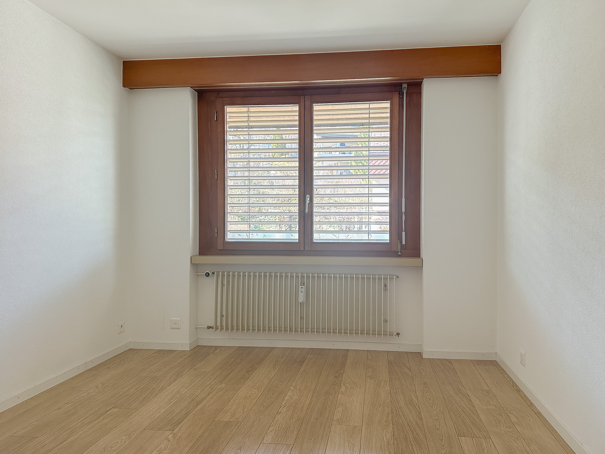Leerer heller Raum mit Fenster und Heizkörper