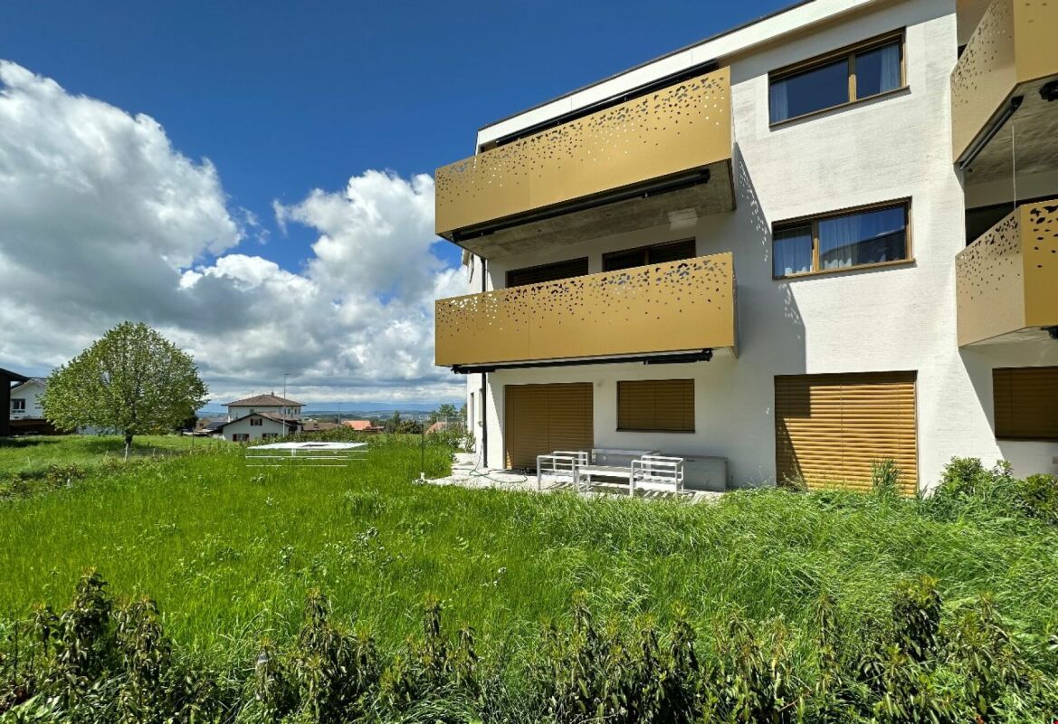 Außenansicht eines modernen Wohngebäudes mit Balkonen und großer Wiese
