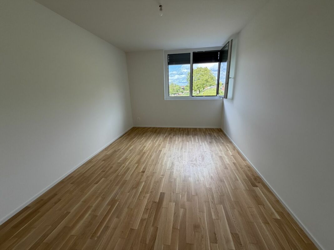 Leerer heller Raum mit Holzfußboden und Fensterblick