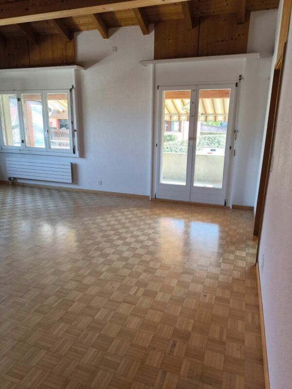 Heller leerer Wohnraum mit Holzdecke und Balkonzugang