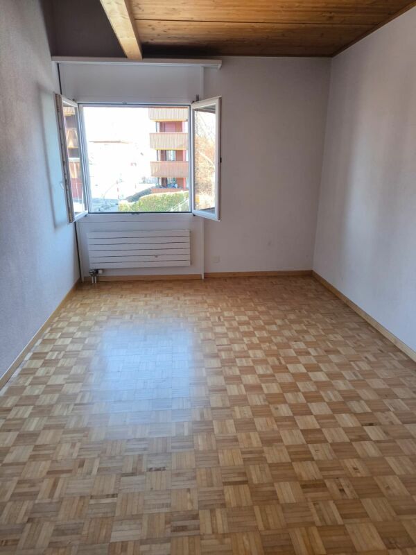 Leerer Raum mit Parkettboden und offenem Fenster