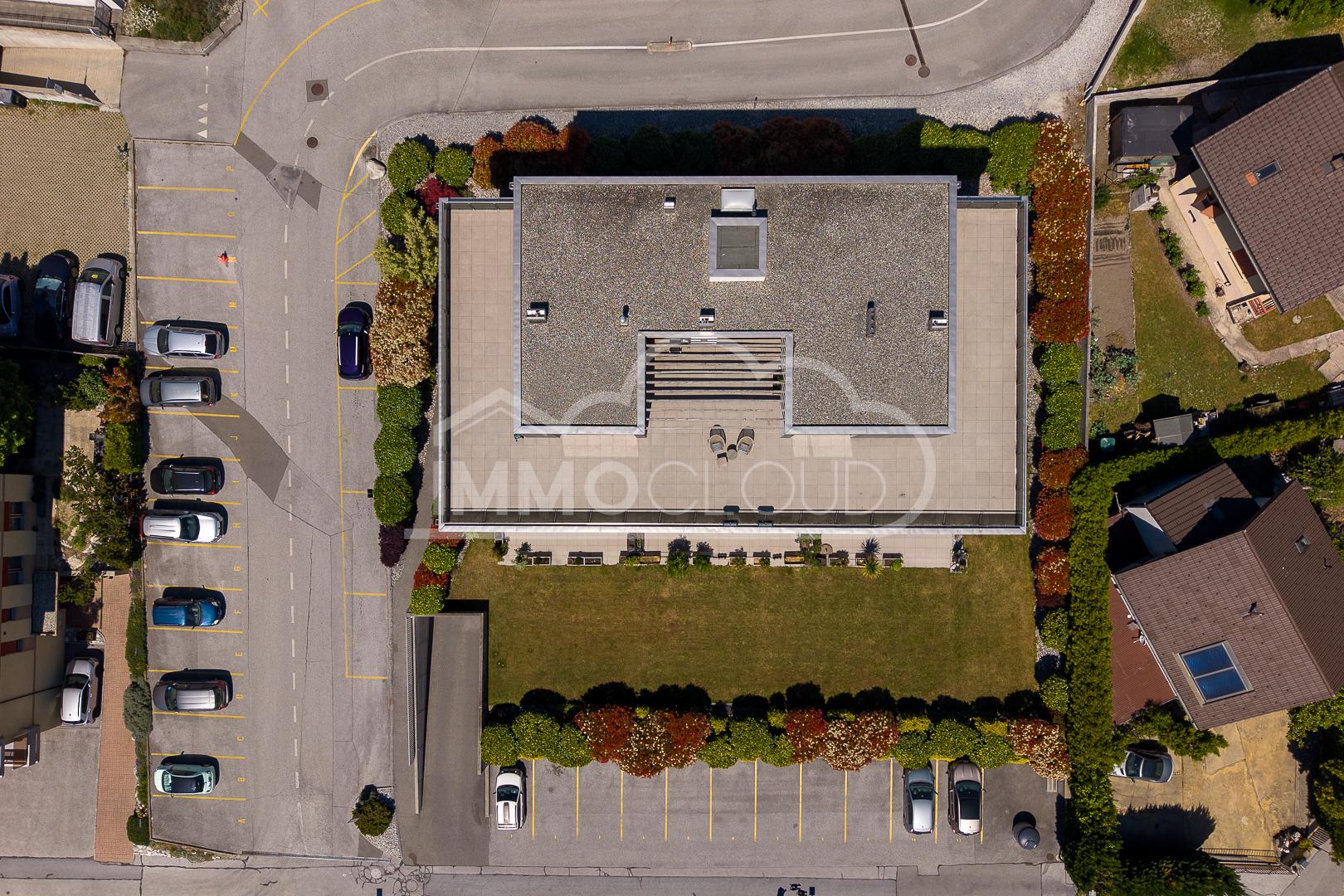 Luftaufnahme eines Wohngebäudes mit Parkplatz und Garten