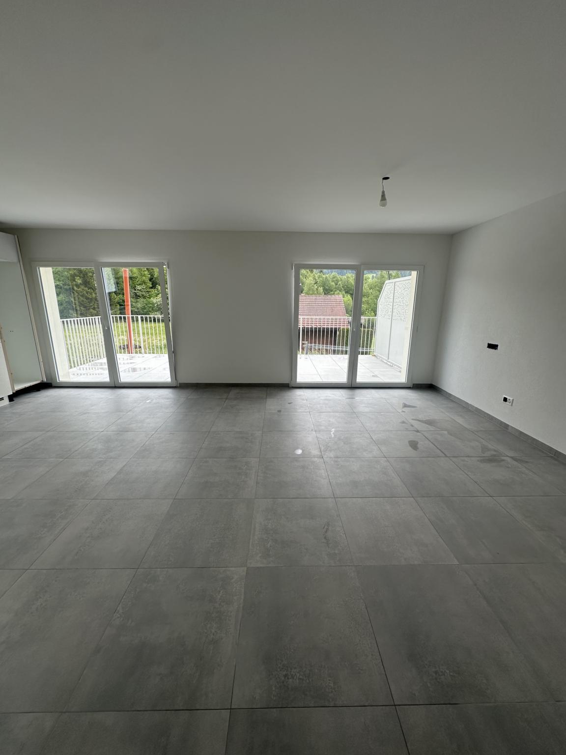 Leerer, modern gefliester Wohnraum mit großer Fensterfront