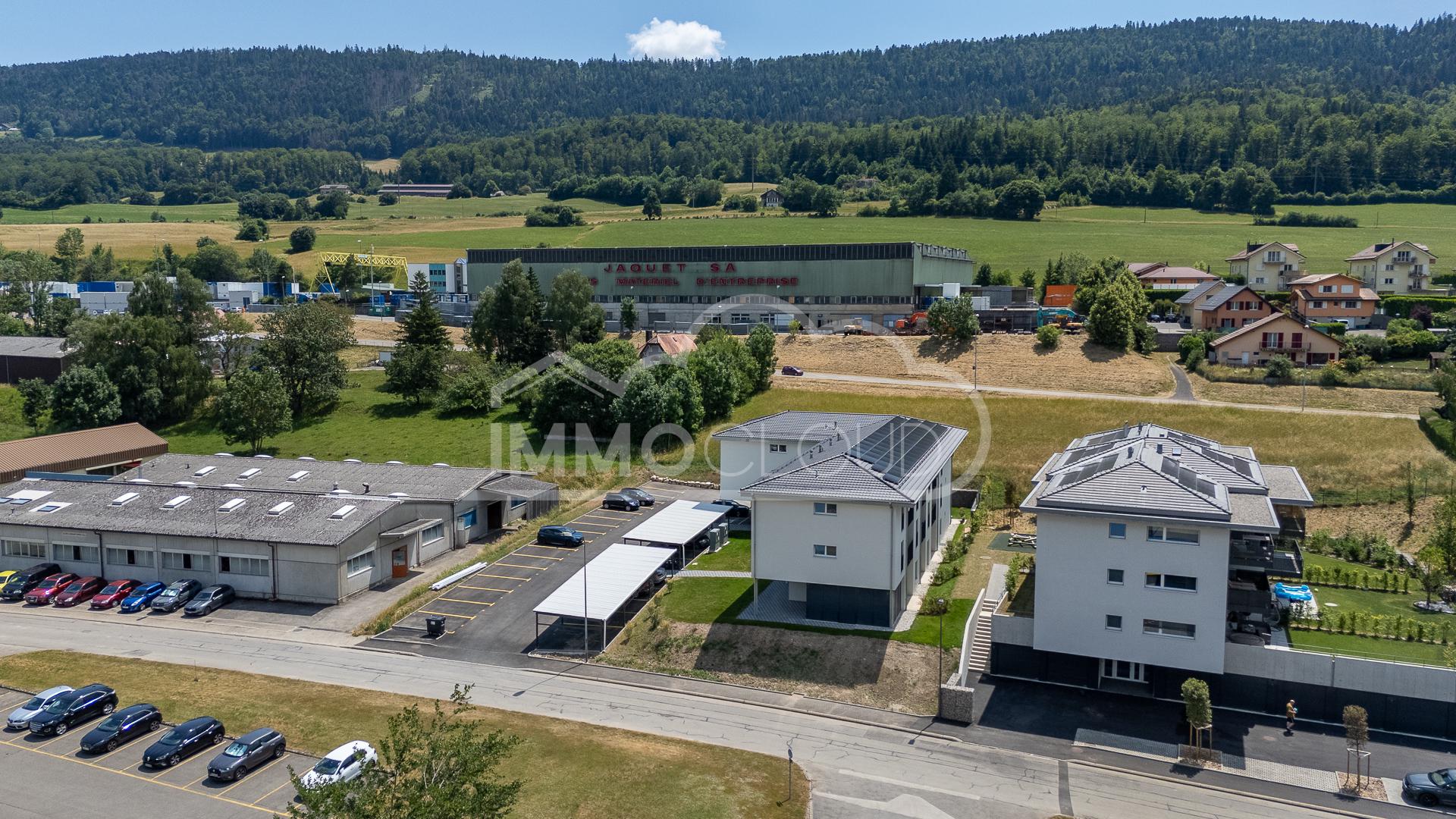 Luftaufnahme eines Wohn- und Gewerbeareals in grüner Hanglage