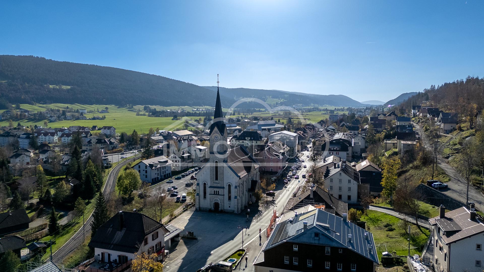 Luftaufnahme eines Dorfes mit Kirche und Talblick