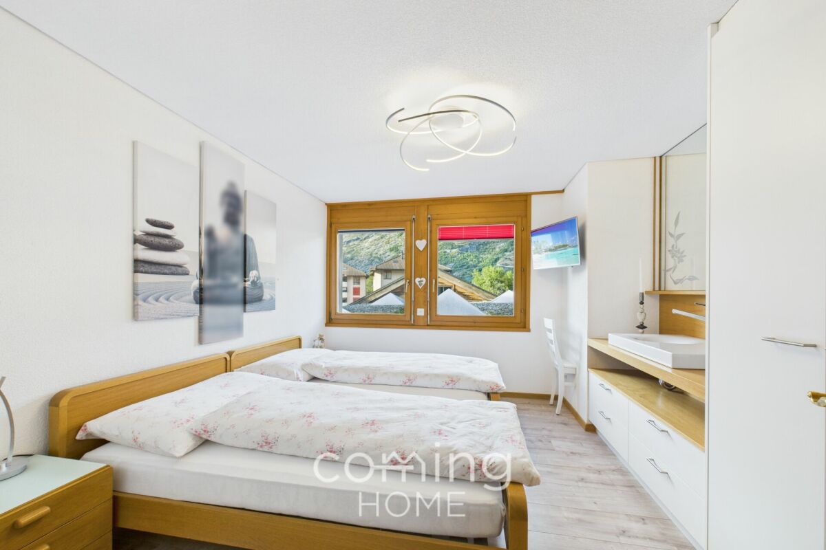 Helles Schlafzimmer mit zwei Betten und Bergblick