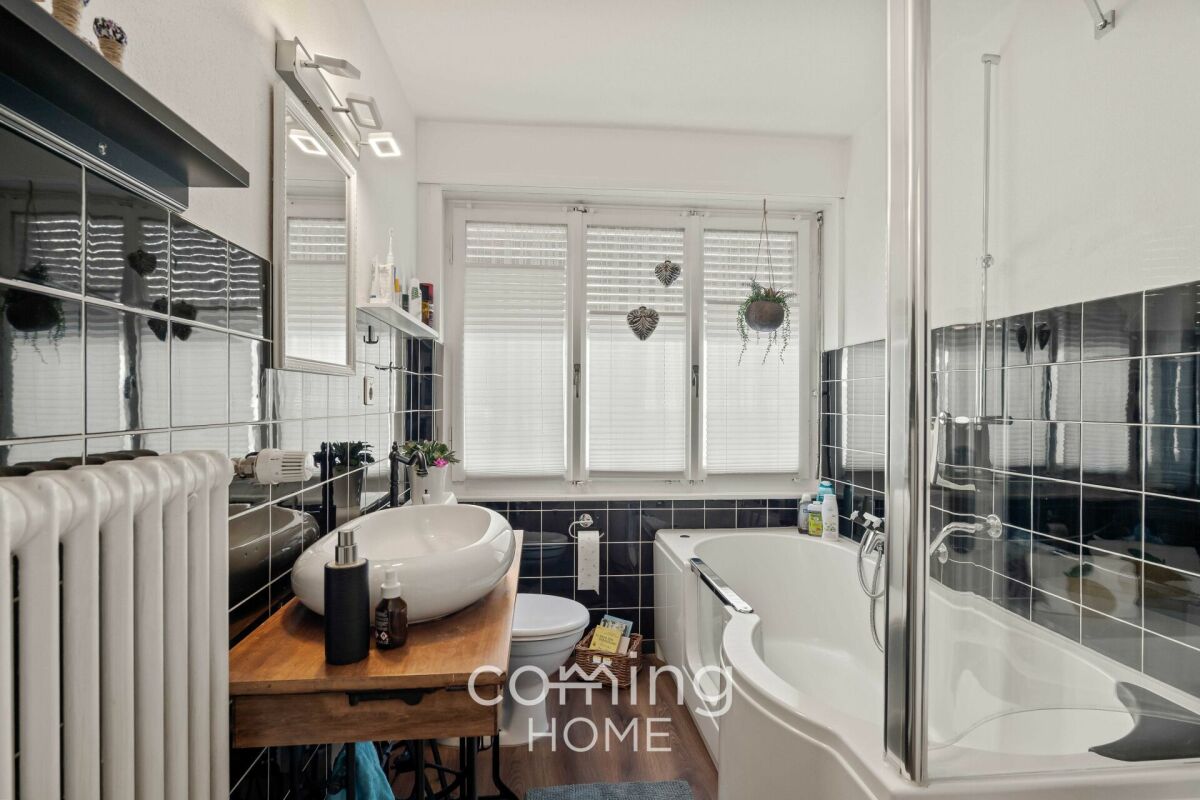 Modernes Badezimmer mit Badewanne und schwarzer Wandverfliesung