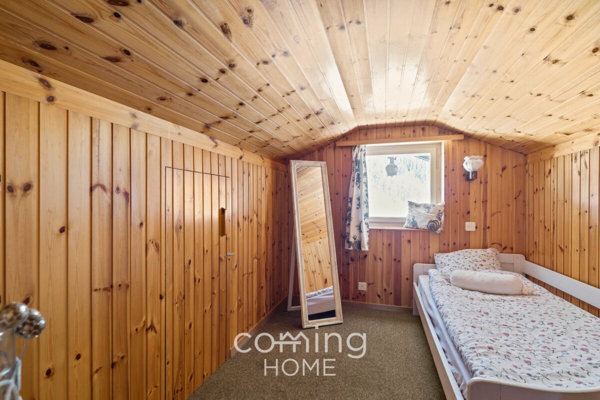 Kleines, holzvertäfeltes Schlafzimmer mit Schrägdecke