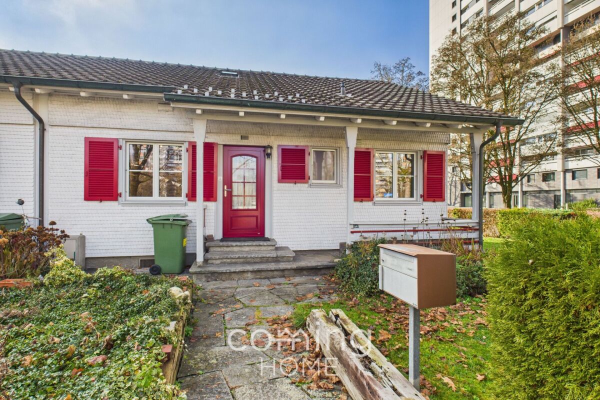 Einfamilienhaus mit weißer Fassade und roten Fensterläden