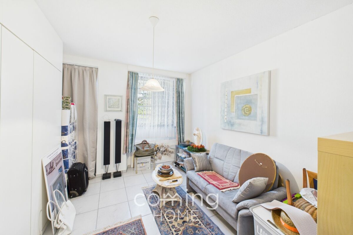 Helles, schmales Wohnzimmer bzw. Wohnbereich mit Sofa und Fenster